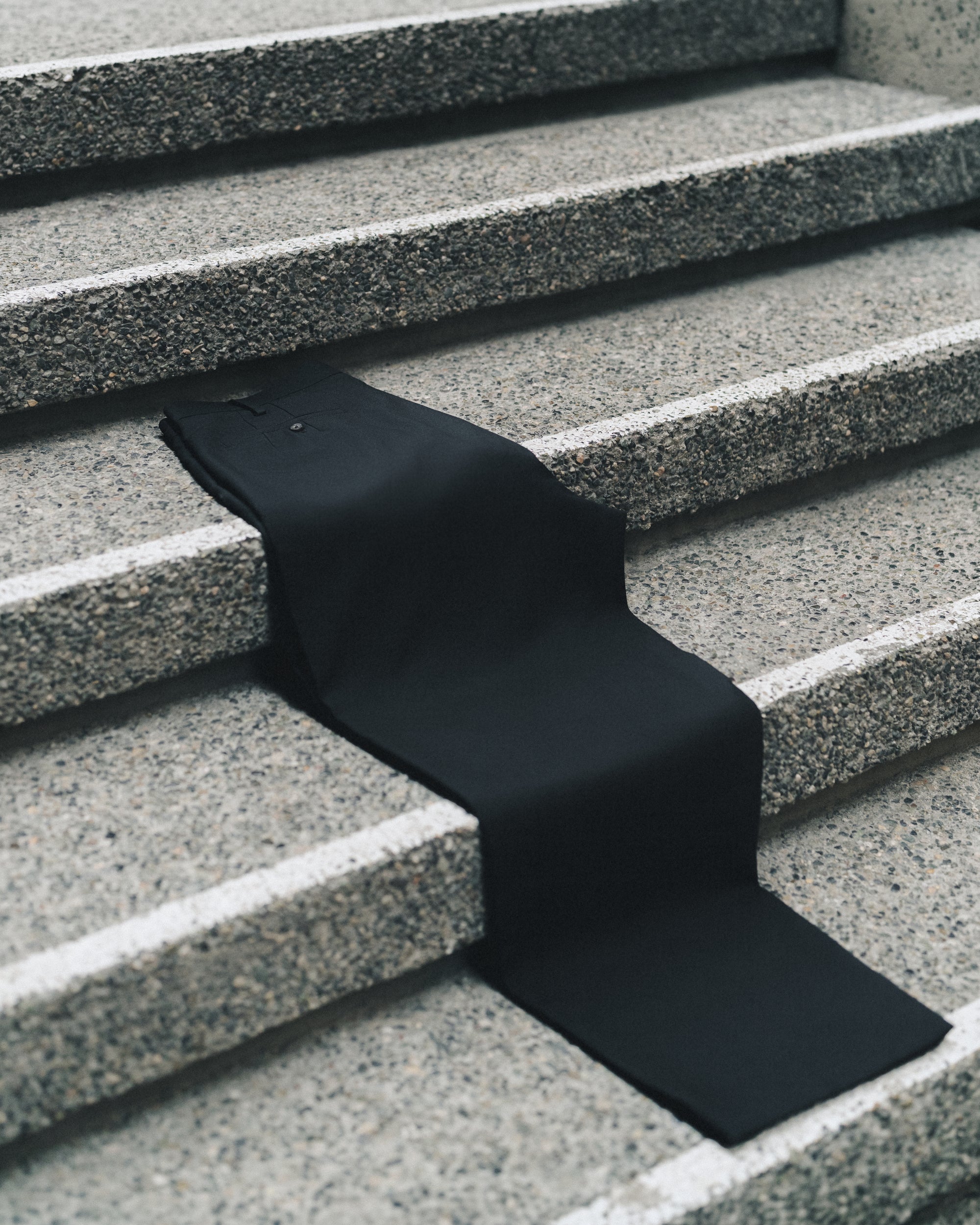 Jiji Pant in Black draped across granite steps