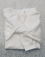 Aki Hoodie in White, folded on a granite surface