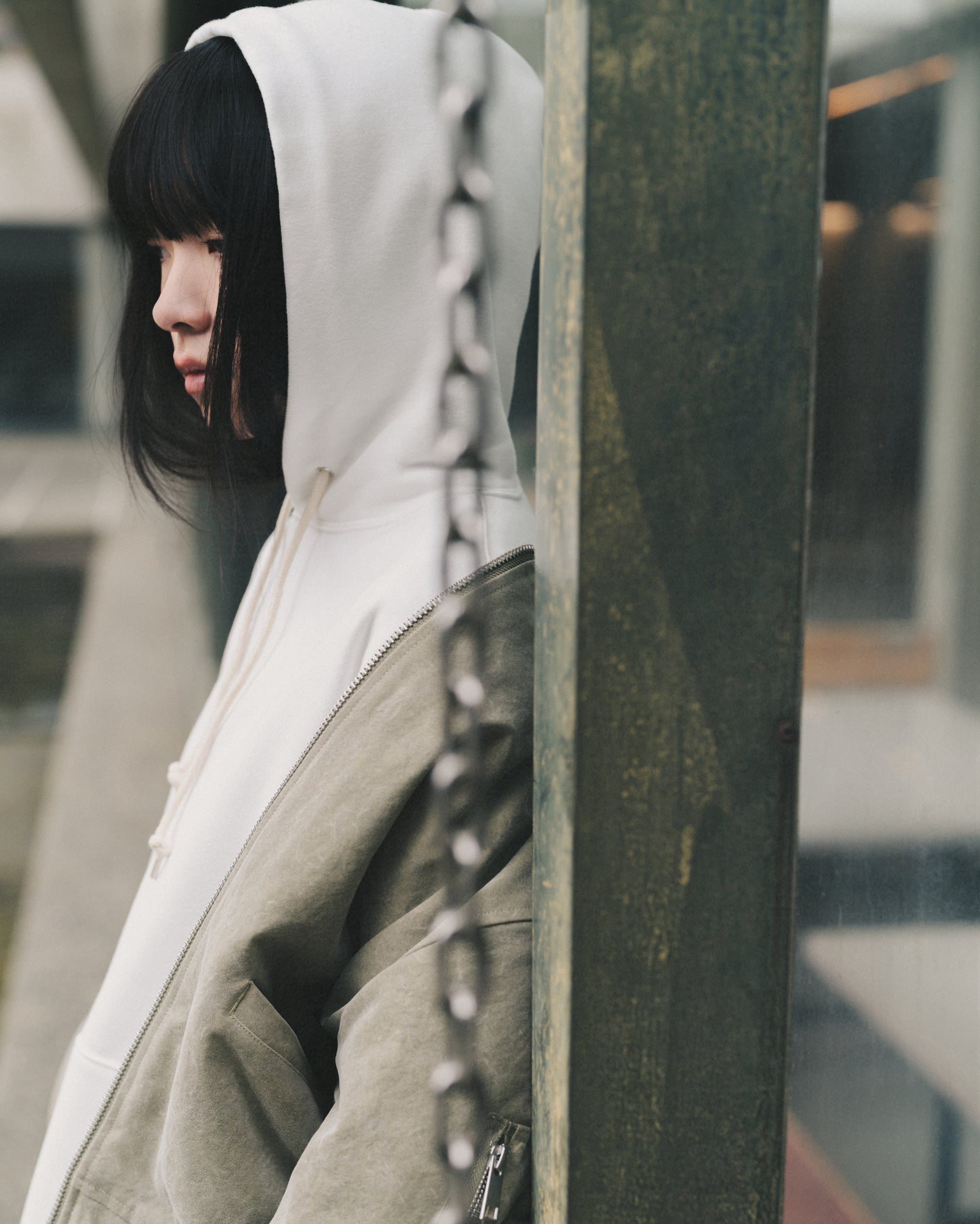 Model wearing the Aki Hoodie in White with the hood up under the Marilyn Bomber in Sage